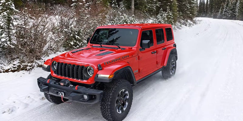 Red 2026 Jeep Wrangler driving through snow